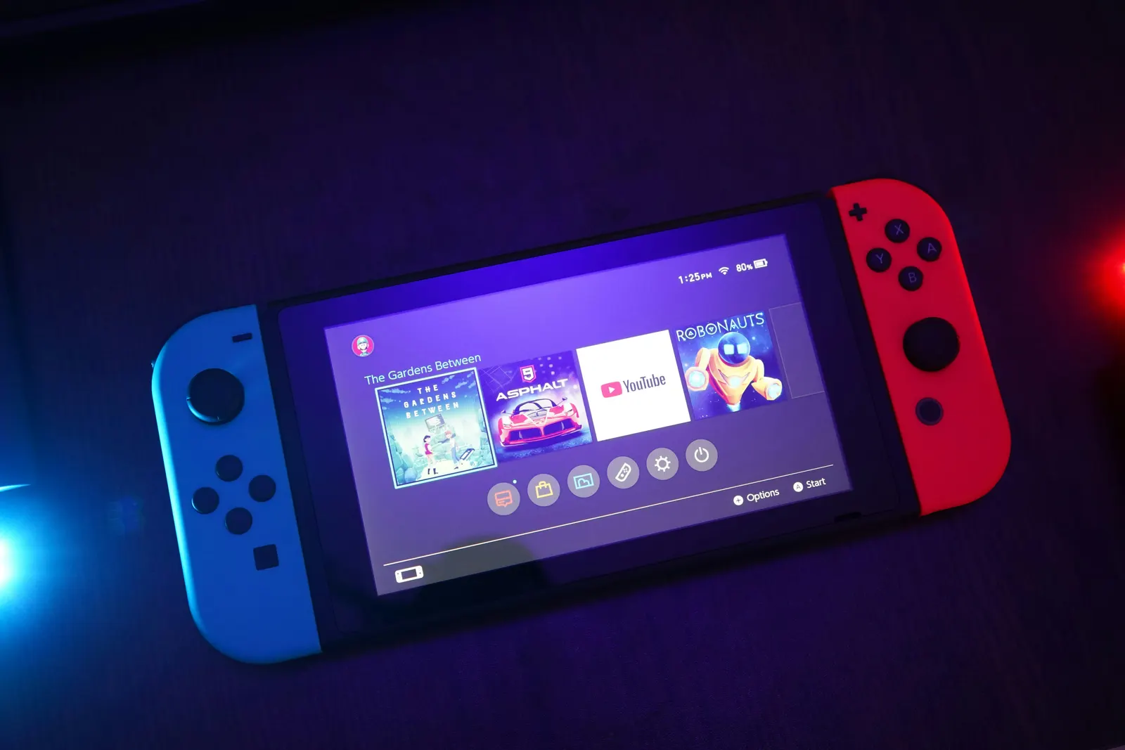 Nintendo Switch in handheld mode with neon blue and red Joy-Cons on the home menu
